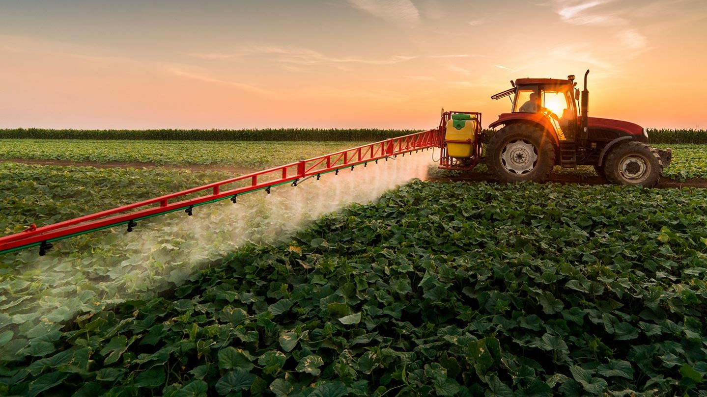 Tractor spraying pesticides on field