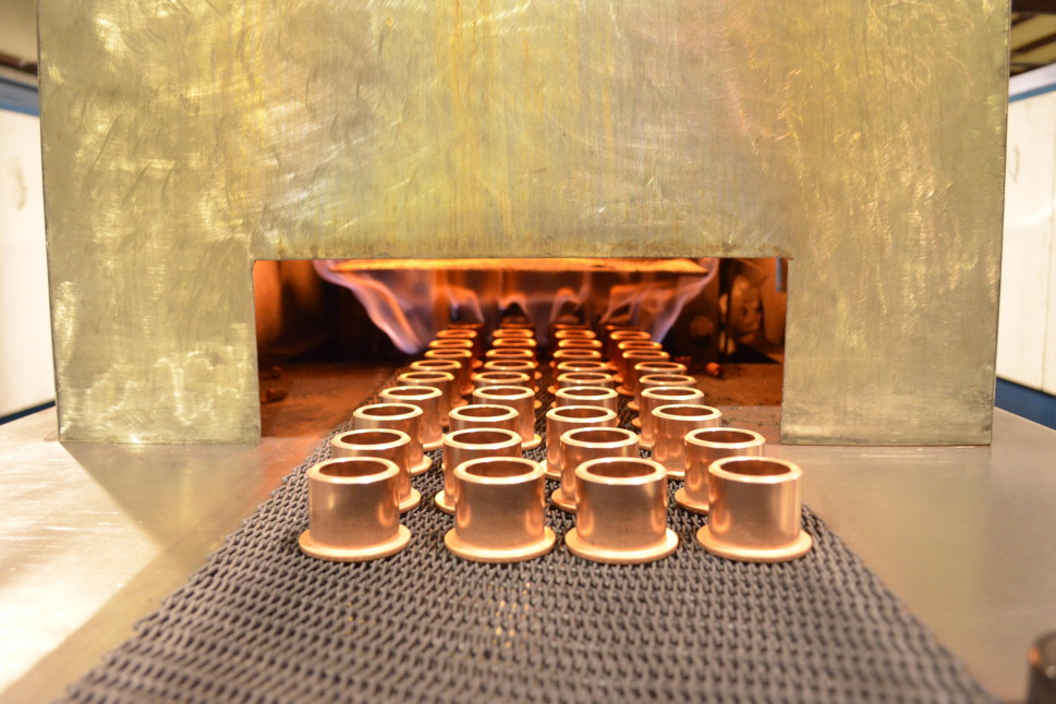 Copper parts entering a continuous sintering furnace